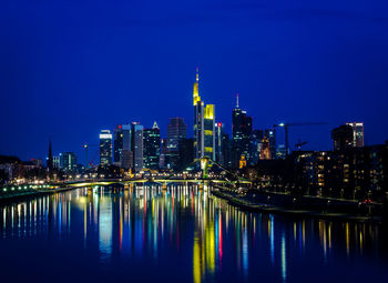 Illuminated cityscape against clear blue sky at night