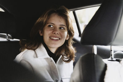 Smiling woman day dreaming while sitting in car on vacation