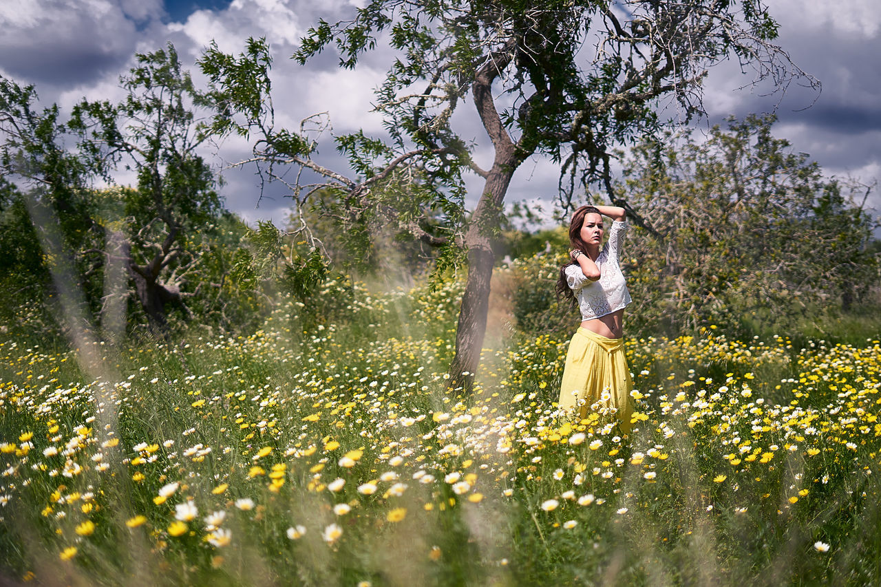 flower, nature, tree, young adult, field, young women, outdoors, beauty in nature, one person, happiness, smiling, leisure activity, meadow, enjoyment, day, yellow, grass, standing, wedding, bride, wedding dress, lifestyles, women, real people, cheerful, beautiful woman, growth, fragility, freshness, sky, adult, one young woman only, people, flower head, adults only