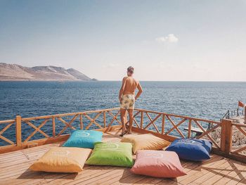 Rear view of shirtless man on beach against sky