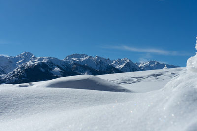 Scenic view of snowcapped mountains against blue sky