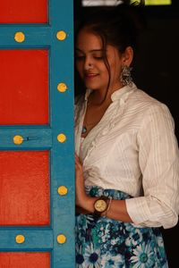 Smiling young woman standing against door