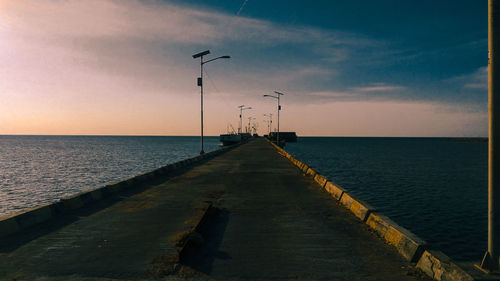 Pier over sea against sky during sunset