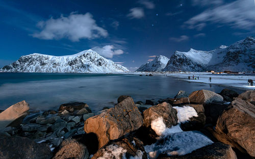 Scenic view of lake by snowcapped mountains against sky