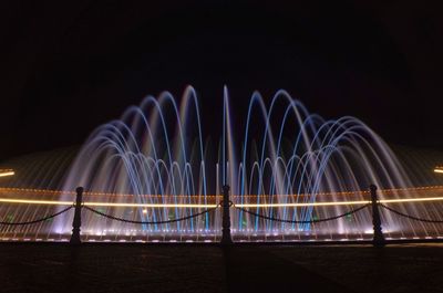 Light trails on bridge against sky at night
