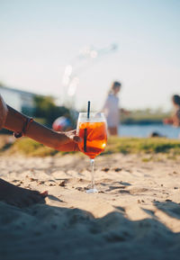 Close-up of hand holding drink at beach