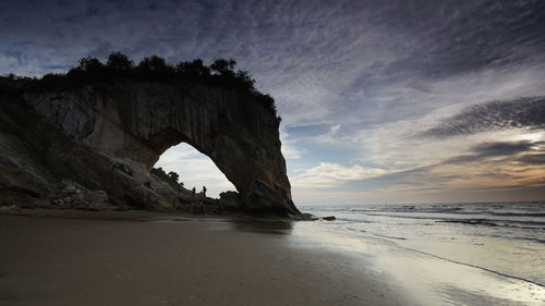 Rock formation on beach against sky