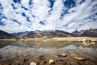 Scenic view of lake by mountains against sky