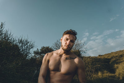 Portrait of young man looking away against sky