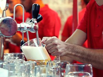 Midsection of man filling glass from beer tap in restaurant
