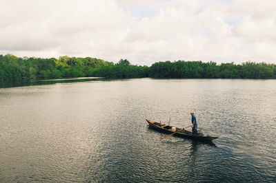 Man in boat on lake against sky