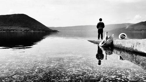 Man standing in water against sky