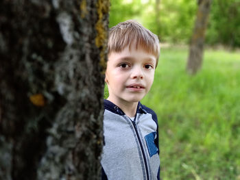 Portrait of cute boy smiling on tree trunk