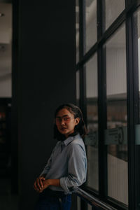 Portrait of smiling woman standing against window