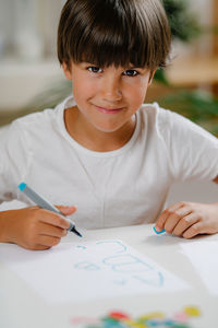 Boy writing letters on preschool screening test.