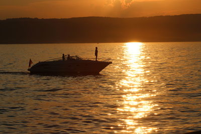 Silhouette boat sailing in sea against sky during sunset