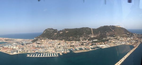 Aerial view of city by sea against sky