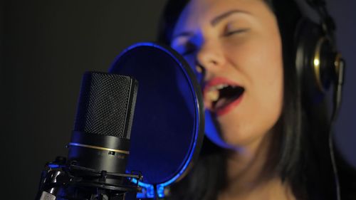 Close-up of woman singing by microphone in studio