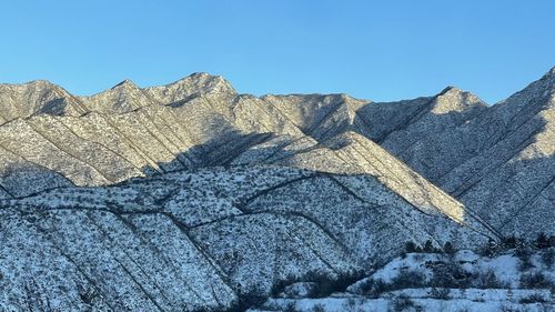 Low angle view of sun shining over mountain against blue sky