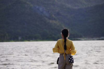 Rear view of woman standing by lake 