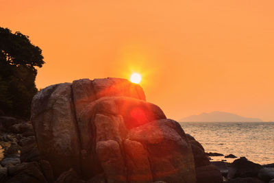 Rock formation in sea against sky during sunset