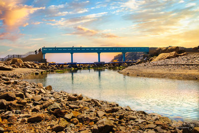 Bridge over river against sky during sunset