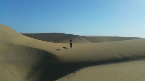 Person riding in desert against clear blue sky