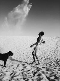 Full length of dog standing on beach against sky