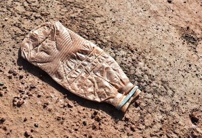 High angle view of weathered water bottle on sand