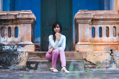 Portrait of woman sitting on steps against door