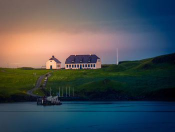 Building by sea against sky during sunset