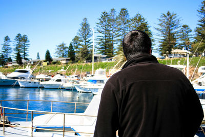 Rear view of man on boat against trees