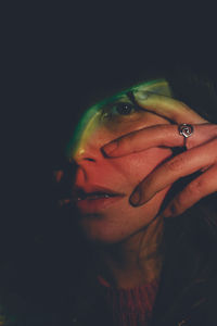 Close-up of young woman against black background