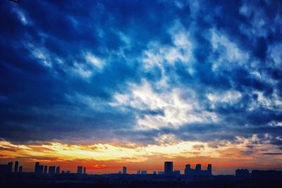 Scenic view of dramatic sky over city at sunset