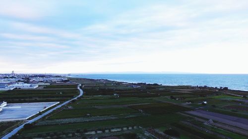 Aerial view of city by sea against sky