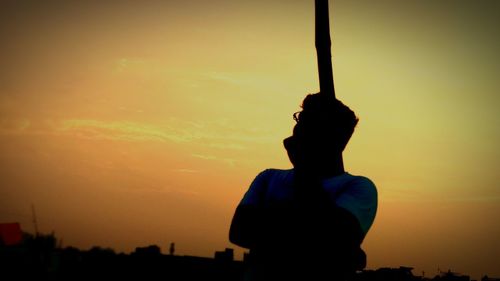 Silhouette man standing against orange sky