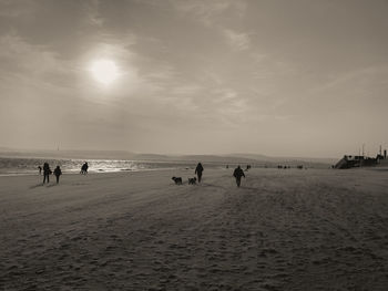 People on beach against sky during sunset