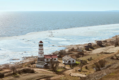 Lighthouse by sea against sky