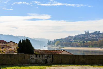 Houses by river and buildings against sky