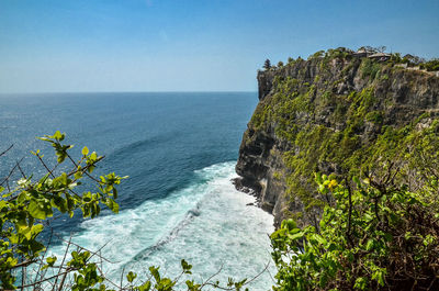 Uluwatu temple on cliff by sea against clear sky