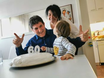 Happy grandparents with grandson enjoying birthday cake on table at home