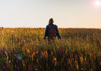 Rear view of woman standing on field against sky