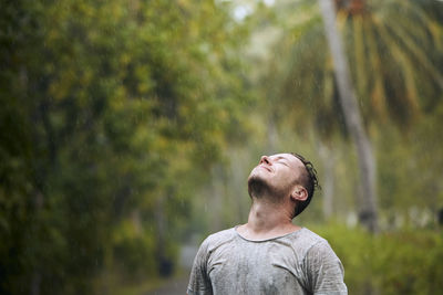 Portrait of young man standing against trees