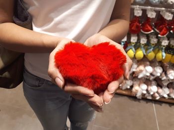 Midsection of woman holding red while standing outdoors