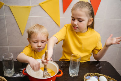 Sister and brother cook in the kitchen, knead the dough, easter holiday