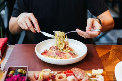 Midsection of man eating food on table