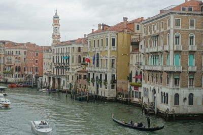 Boats in canal by buildings in city