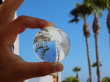 Low angle view of person holding crystal ball against sky