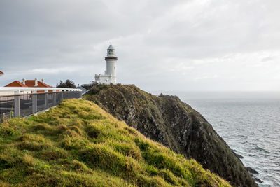 Lighthouse amidst sea and buildings against sky