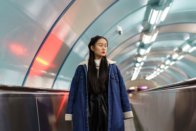 Asian girl in underground. trendy young female in stylish outfit on escalator ride to subway station